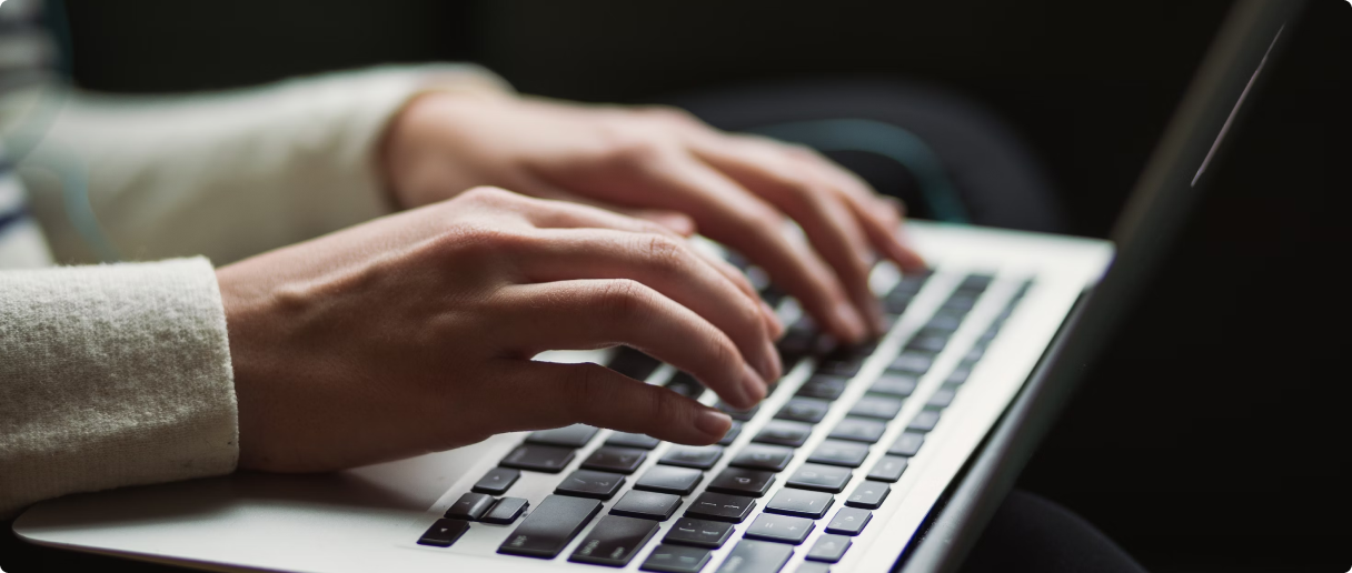 Hands typing on a laptop keyboard